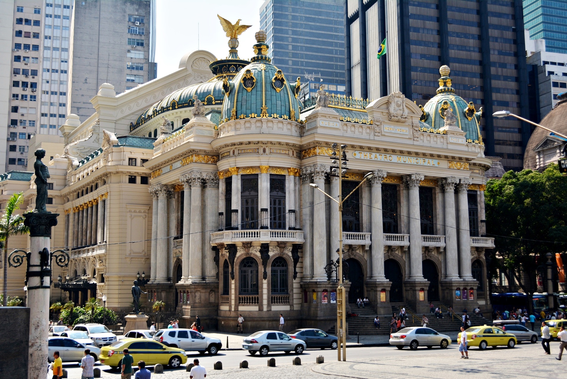 Vista do Theatro Municipal do Rio de Janeiro, edifício em estilo eclético com colunas coríntias, cúpulas verde-esmeralda e ornamentos dourados