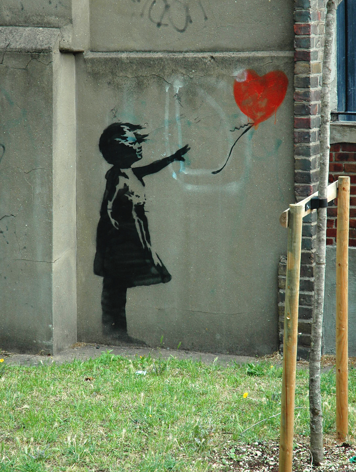 street art Mural “Girl with Balloon”, do artista britânico Banksy, mostrando a silhueta de uma menina em preto e branco soltando um balão vermelho em forma de coração