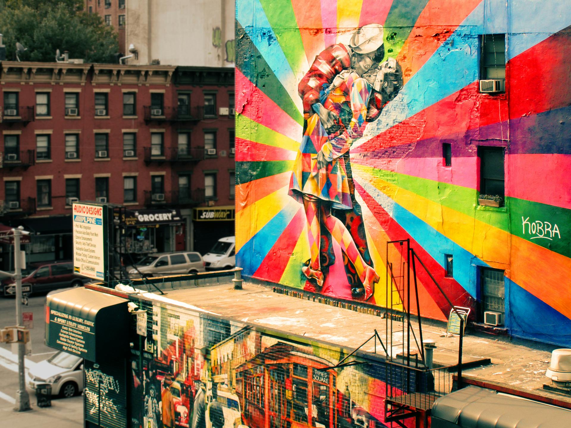 street art Mural “O Beijo” (2012), do artista brasileiro Eduardo Kobra, em Nova York. A pintura colorida e geométrica retrata um marinheiro beijando uma enfermeira, inspirada na foto icônica do fim da Segunda Guerra Mundial