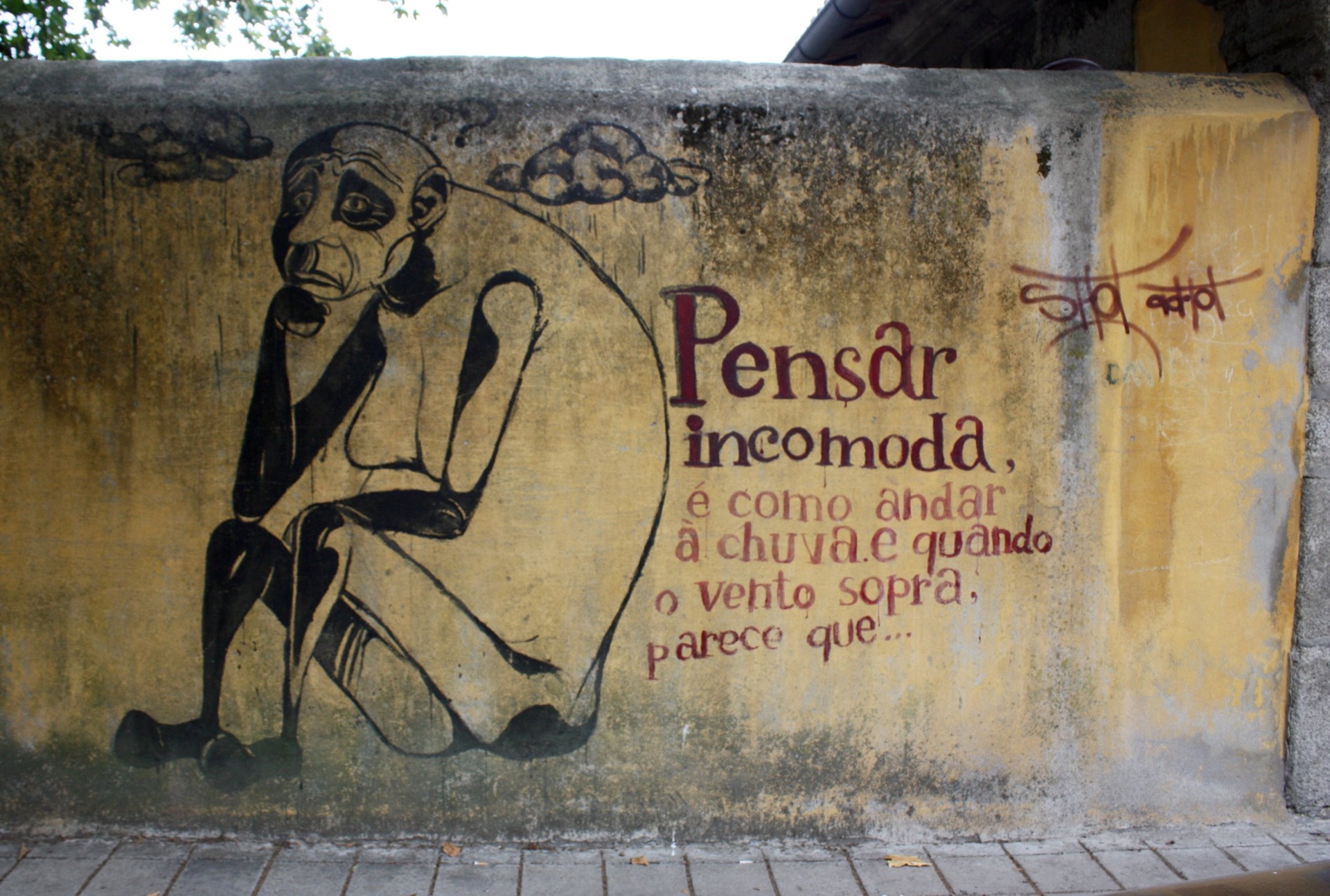 street art Muro com arte de rua retratando uma figura humana pensativa ao lado do texto “Pensar incomoda, é como andar à chuva e quando o vento sopra, parece que...”