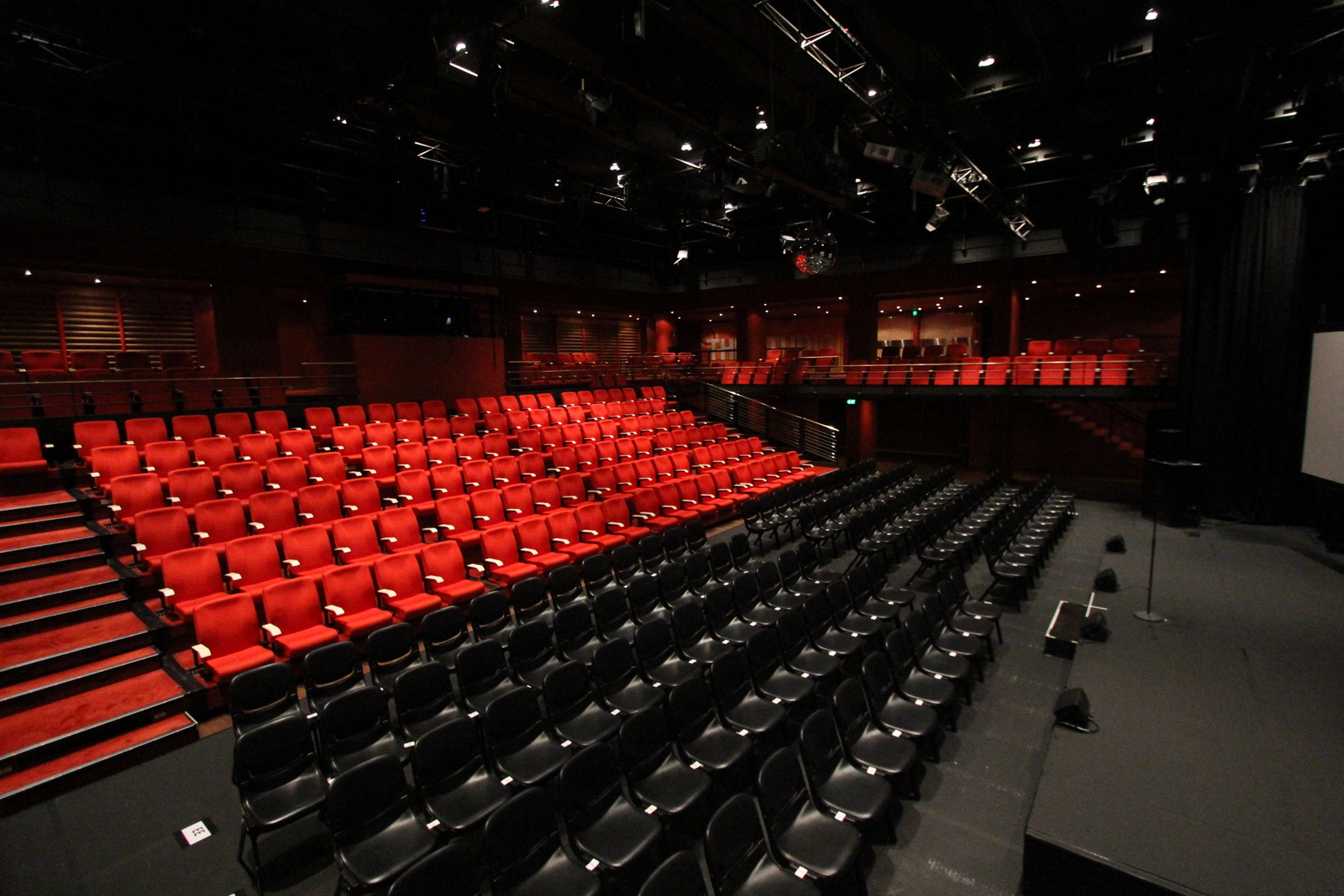 Vista interna do Studio da Sydney Opera House, com fileiras de assentos pretos e vermelhos, palco amplo e estrutura flexível, ideal para shows intimistas, performances multimídia e eventos híbridos