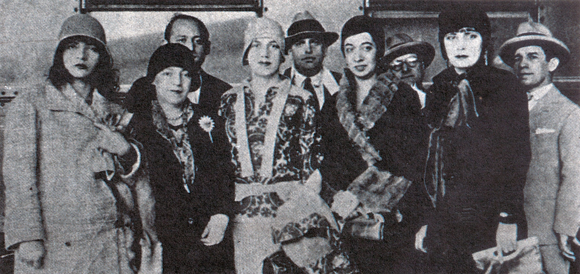 Fotografia em preto e branco registrada durante a exposição de Tarsila do Amaral no Rio de Janeiro, em 1929. Os artistas e intelectuais posam juntos diante das obras, vestindo trajes elegantes típicos da década de 1920. Da esquerda para a direita: Pagu, Anita Malfatti, Tarsila do Amaral, Oswald de Andrade, Elsie Houston, Benjamin Péret e Eugênia Álvaro Moreyra