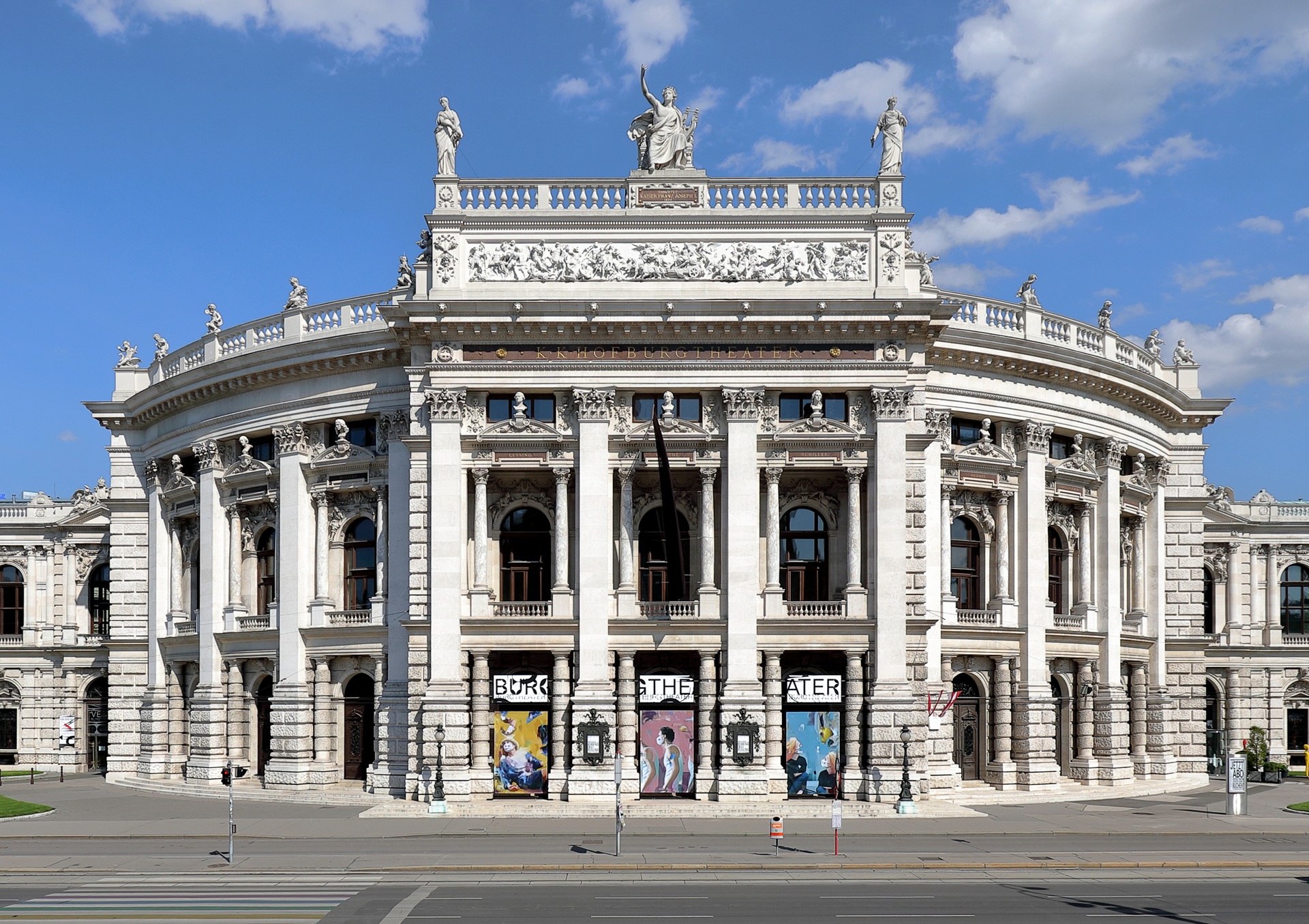 Fachada principal do Burgtheater, em Viena, Áustria, com colunas, esculturas e detalhes ornamentais em estilo neobarroco, sob um céu azul claro