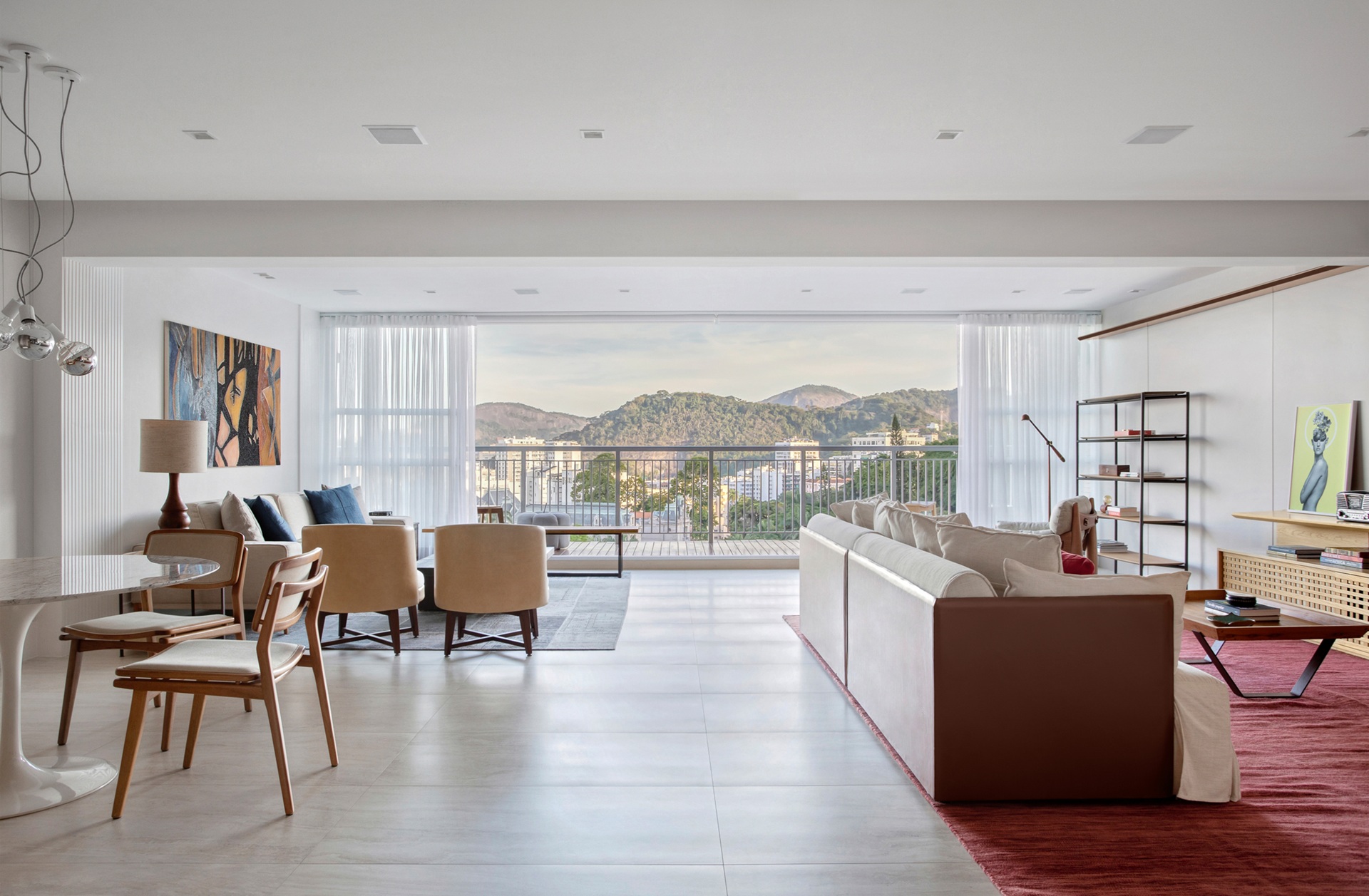 Living de apartamento com duas salas e mesa de jantar redonda, com vista para a paisagem carioca