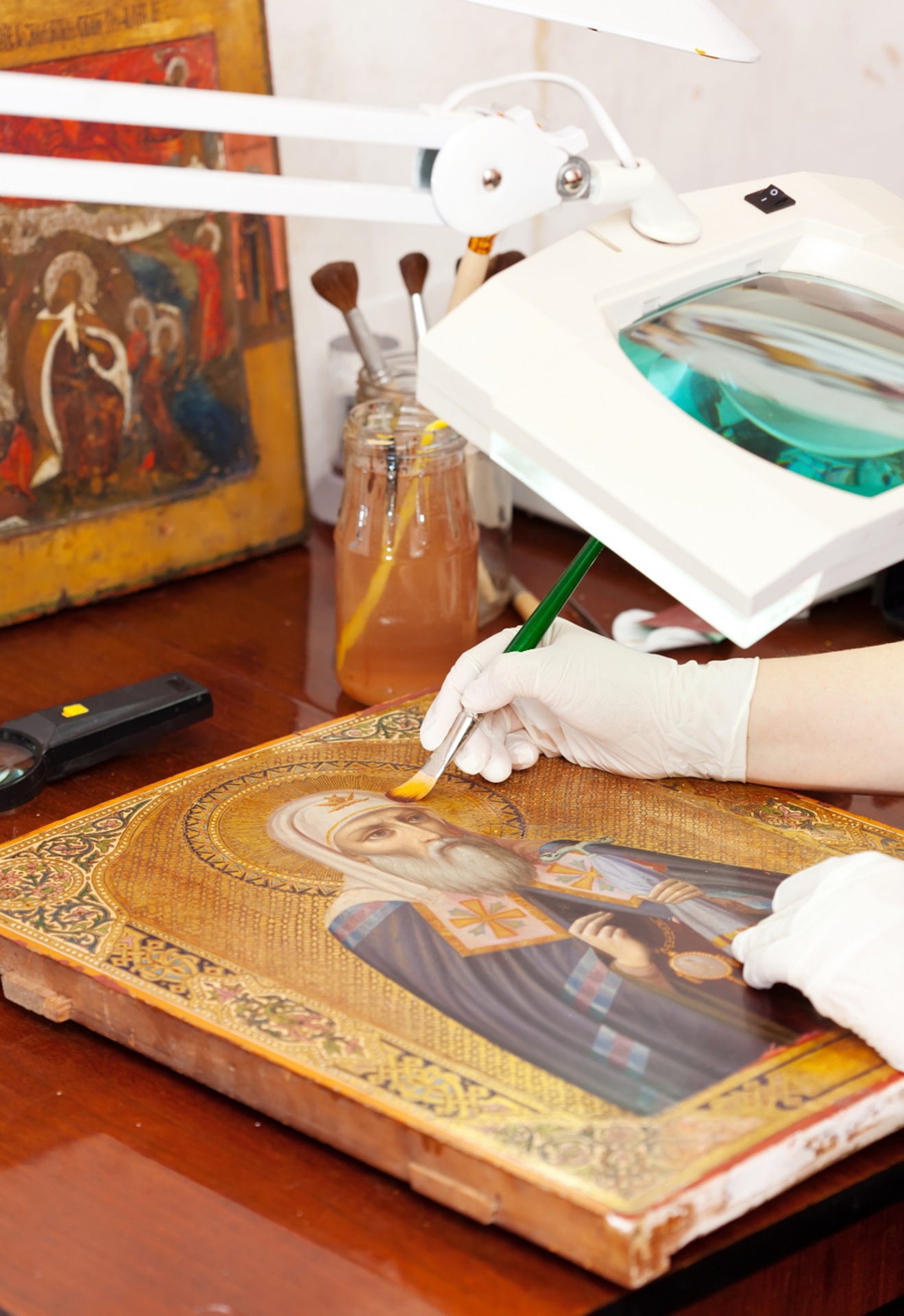 vitrais na arquitetura Pessoa com luvas brancas utiliza pincel fino em uma pintura religiosa sobre vidro