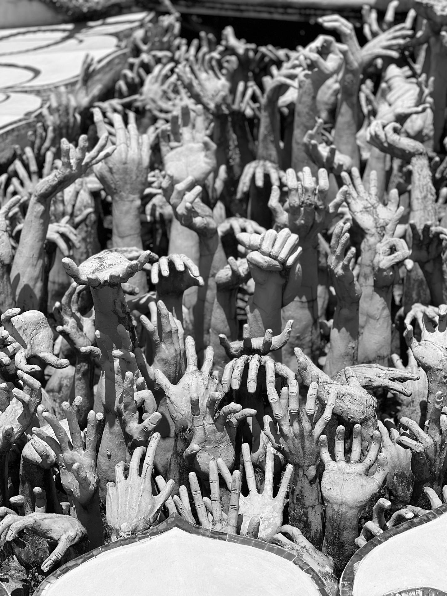 Escultura de mãos brancas no Wat Rong Khun, representando almas presas no ciclo de sofrimento e tentação