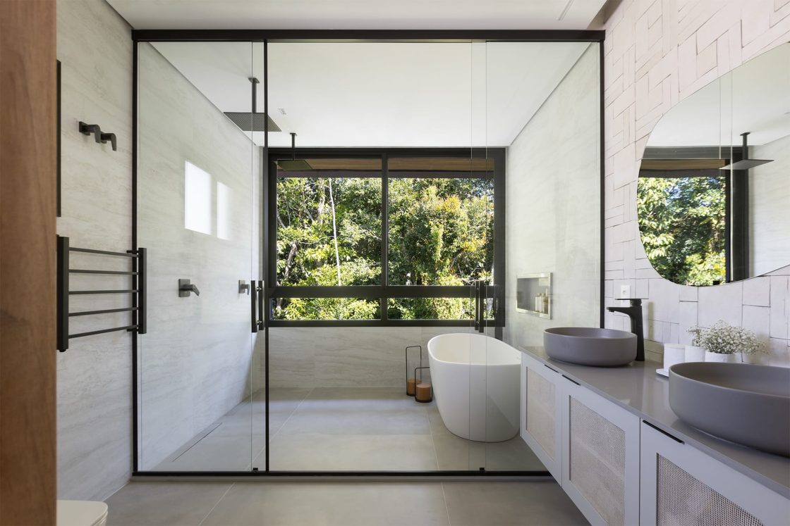 Banheiro amplo com banheira de imersão e vista para a mata ao fundo