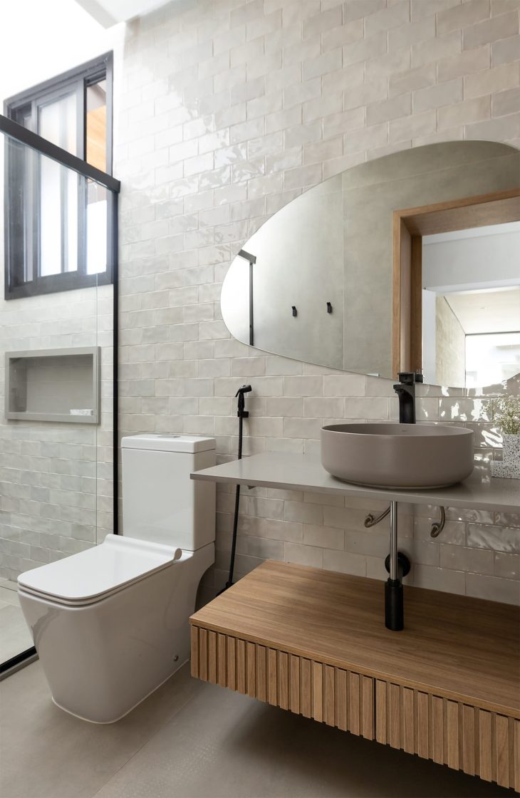 Banheiro em tons neutros com cuba e bancada cinzas sobre móvel de madeira