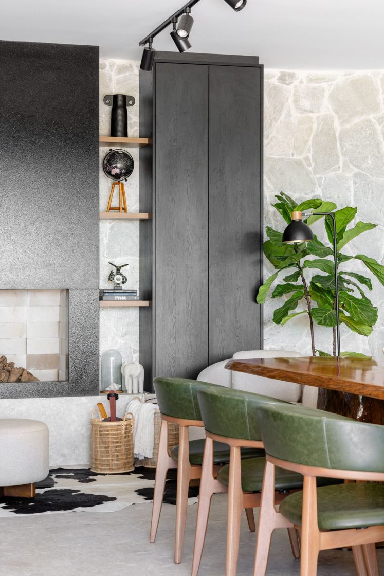 Detalhes de living com estofados claros e móveis escuros, integrados à mesa de jantar de madeira com cadeiras com estofado verde
