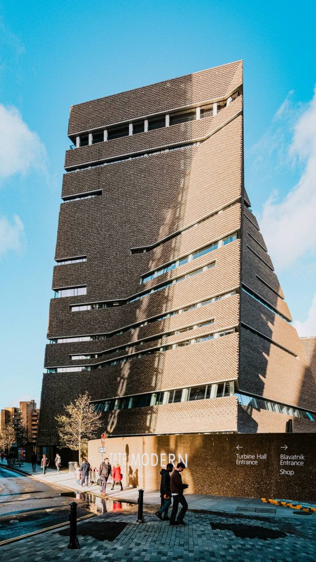 Fachada do museu Tate Modern, com pessoas passando pela calçada