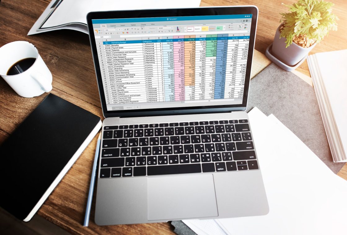 Laptop sobre mesa de trabalho com planilha sendo exibida na tela