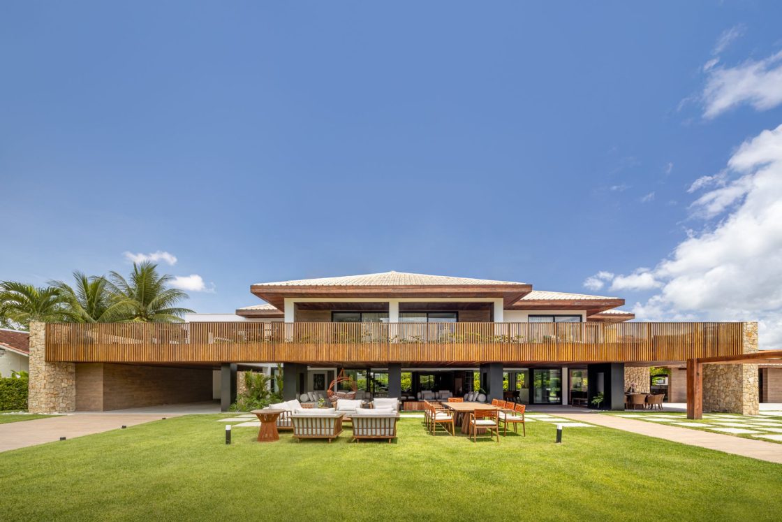 Casa Terraço de frente, vista do jardim, com mesa de jantar e área de convivência com sofás e poltronas