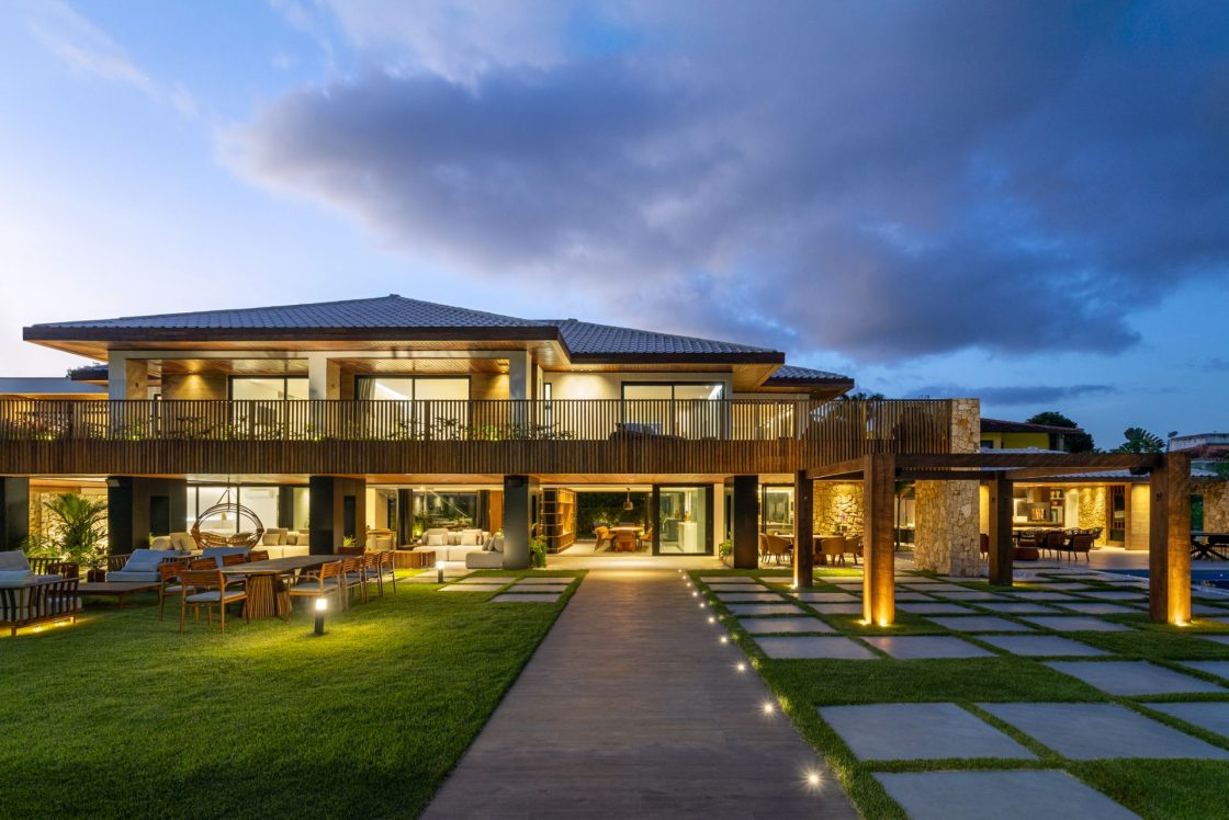 Casa de dois pavimentos com telhado colonial vista de frente, com destaque para caminho em porcelanato que reproduz madeira