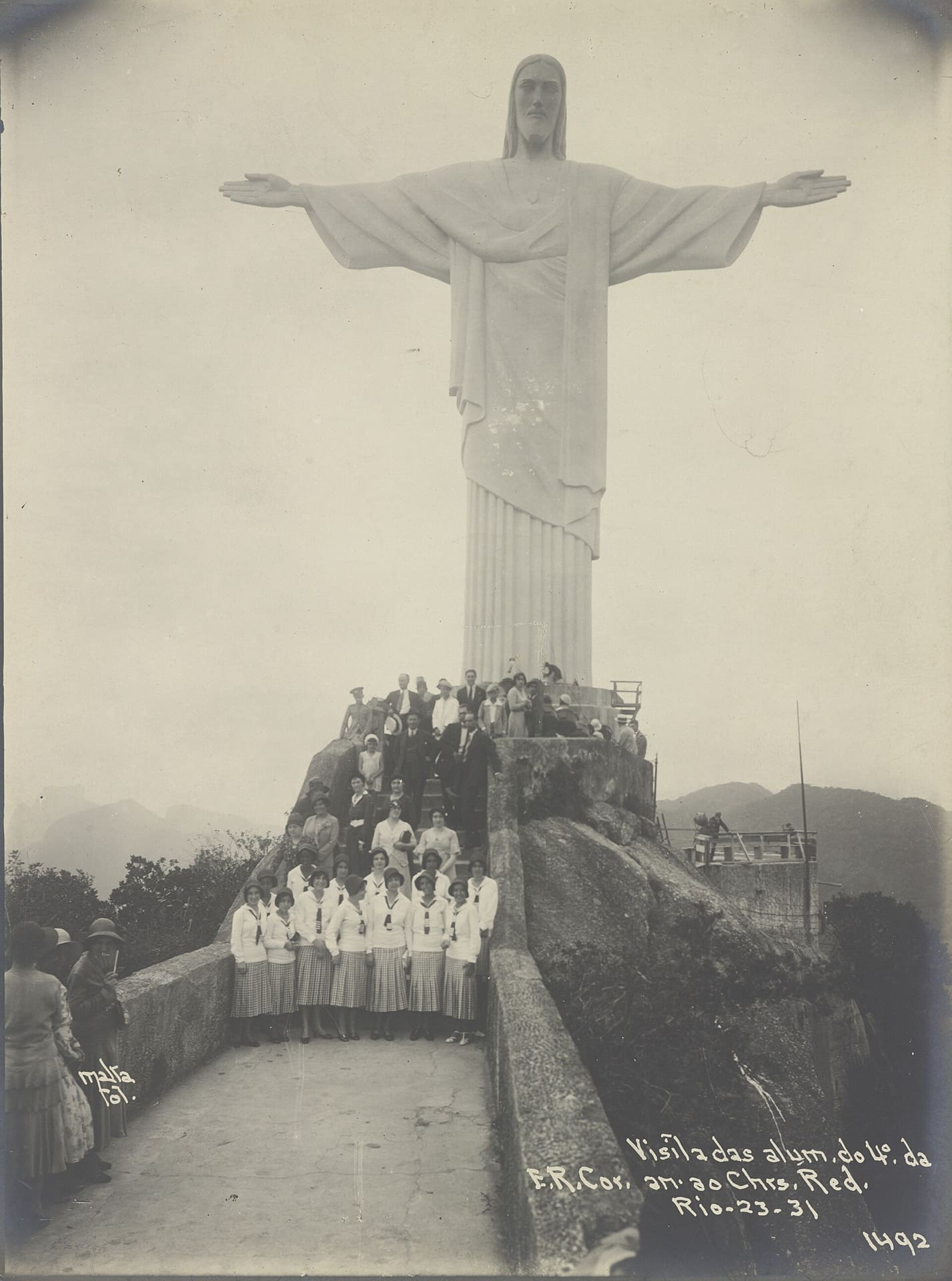 Fotografia de 1931 com grupo de estudantes posando na base do Cristo Redentor durante a inauguração, com a estátua ao fundo e visitantes reunidos na plataforma