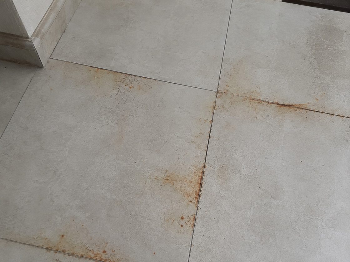 Detalhe de piso cinza em porcelanato com ferrugem em suas bordas
