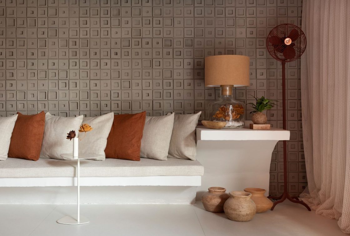 Living contemporâneo com uma parede texturizada ao fundo com paginação geométrica com relevos quadrados em tom cinza-aquecido