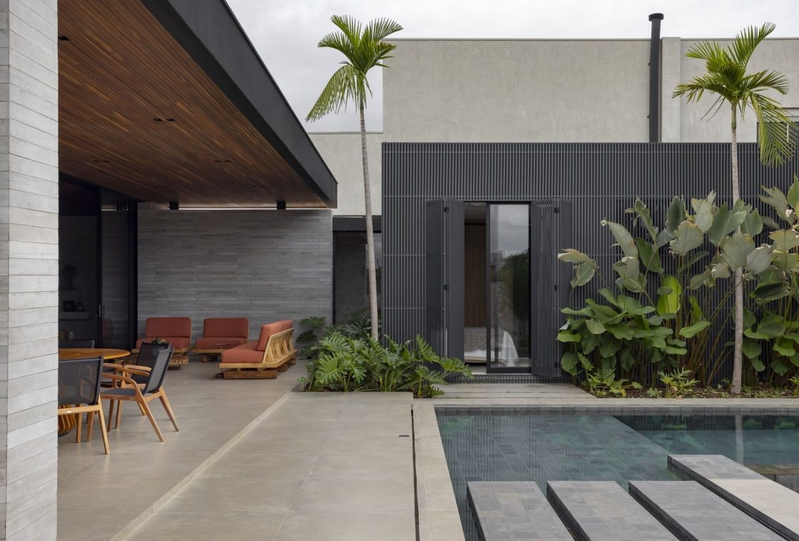 Integração entre ambiente interno e externo, com varanda coberta e uma piscina com plantas ao redor