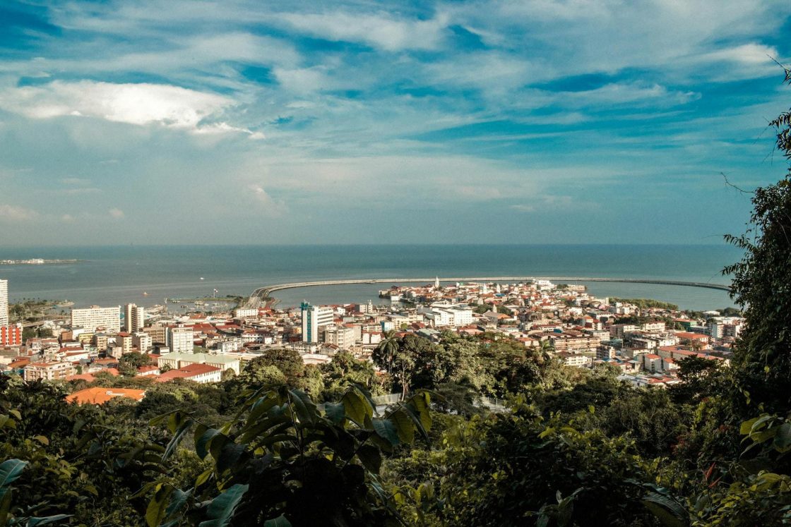 Vista panorâmica de Downtown Amador, com área urbana próxima ao mar, cercada por vegetação tropical sob céu azul com nuvens espalhadas