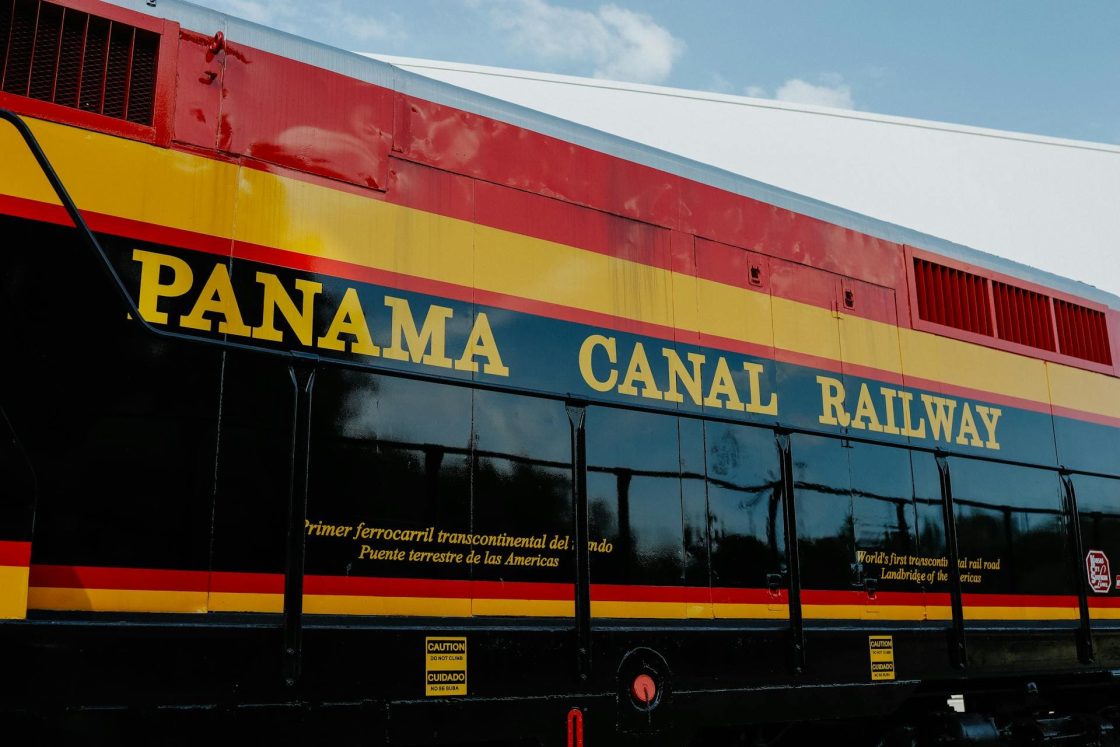 Locomotiva do Panama Canal Railway nas cores vermelho, amarelo e preto, com nome da ferrovia destacado na lateral, sob céu azul claro