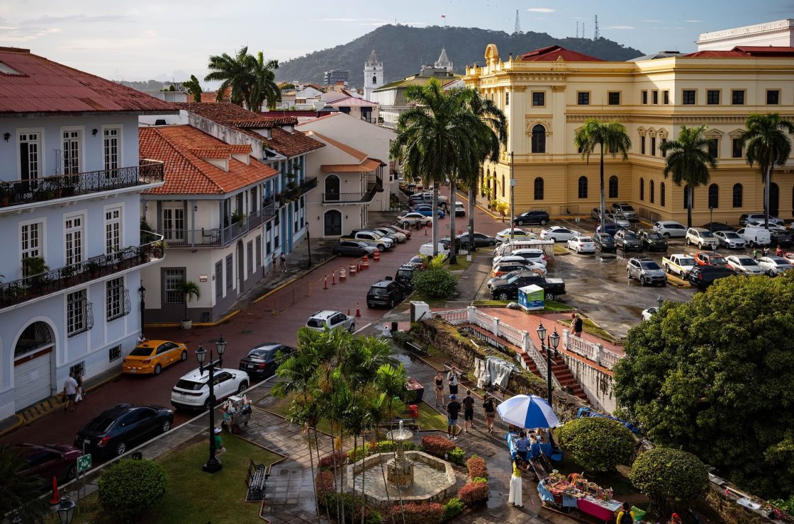 Vista elevada do bairro Casco Viejo, na Cidade do Panamá, com edifícios históricos coloridos, palmeiras, praça arborizada e construções coloniais ao fundo, diante de montanhas verdes