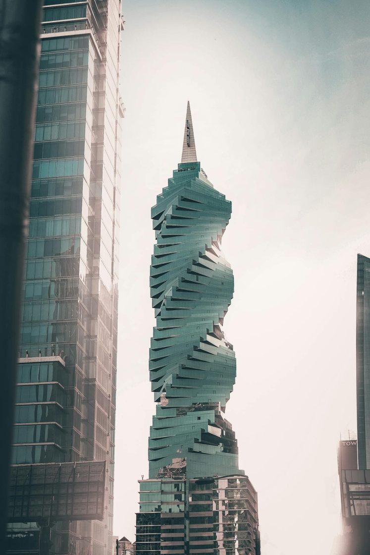 F&F Tower, arranha-céu em formato espiral revestido por vidro esverdeado, cercado por edifícios modernos na Cidade do Panamá sob a luz suave do fim do dia