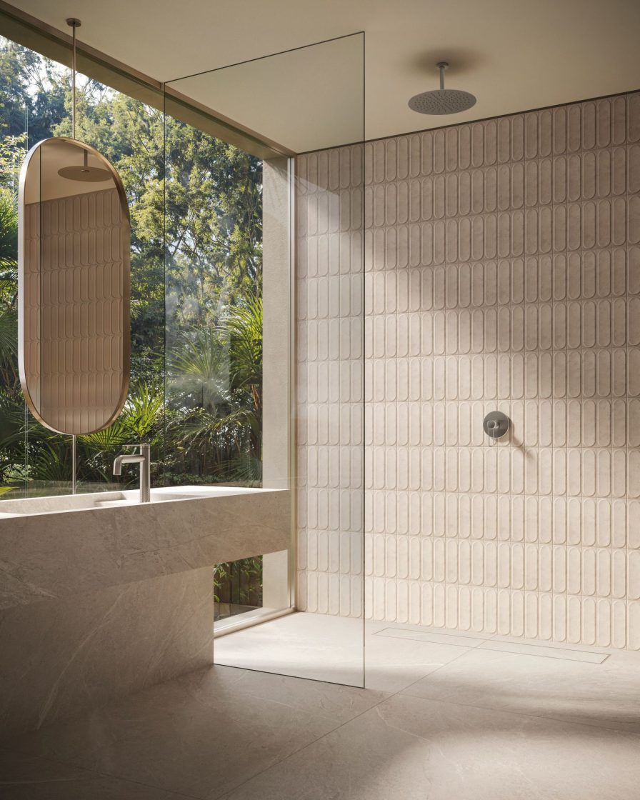 Banheiro em tom off-white com parede em vidro e vista para paisagismo externo em frente a bancada de porcelanato com cuba lateral