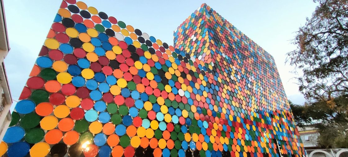 Fachada do Centro Nacional de Arte, Artesanato e Design, em Mindelo, formada por 2.532 peças metálicas coloridas e recicladas que filtram a luz e criam uma composição inspirada na música