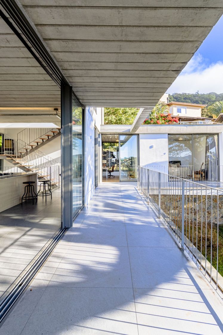 Varanda de casa que conecta diferentes ambientes, como sala, cozinha e quarto