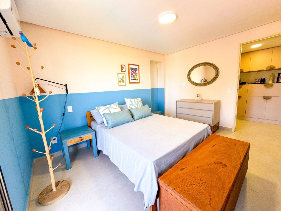 Quarto de casal com meia parede em azul e bege e ampla abertura que leva ao closet