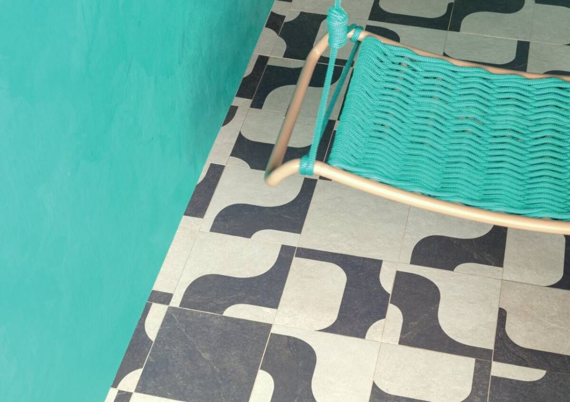 Detalhe de piso decorado em preto e off-white, com espreguiçadeira turquesa em cima