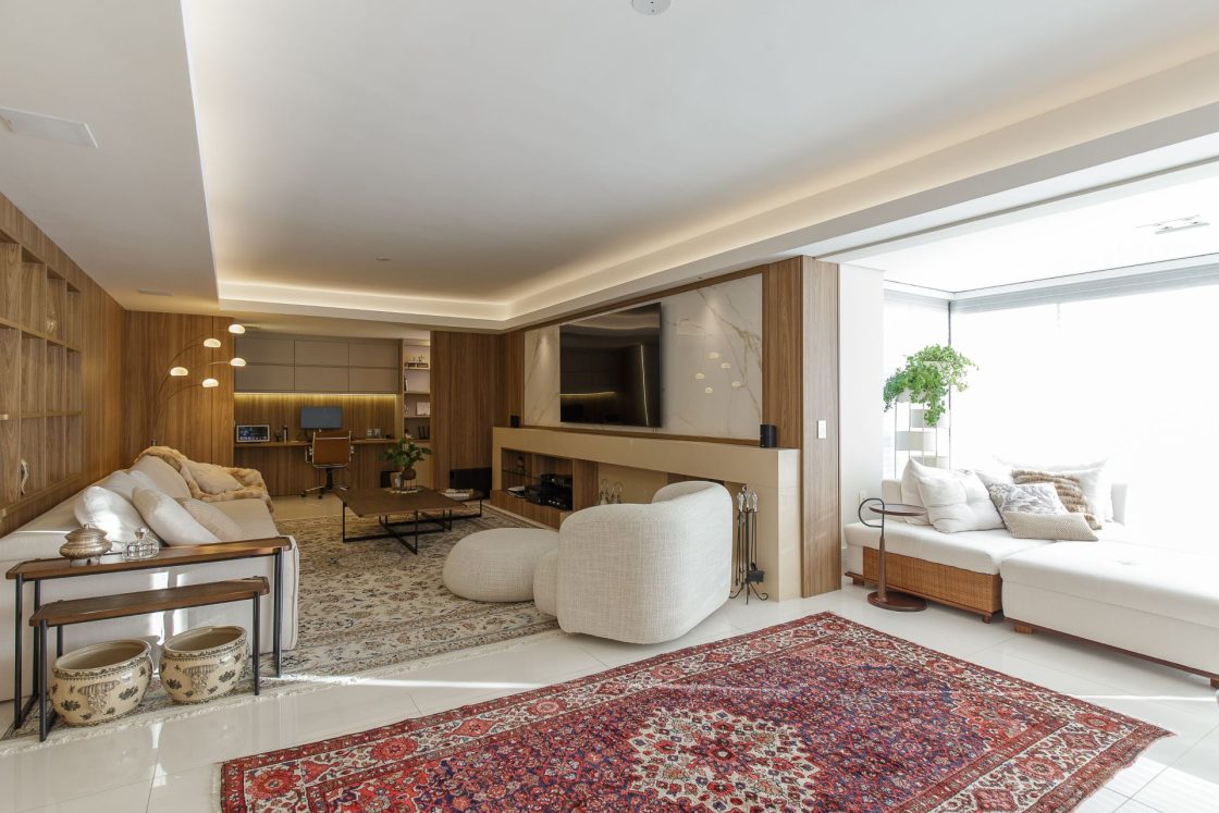 Living com dois ambientes delimitados por tapetes, com home office ao fundo