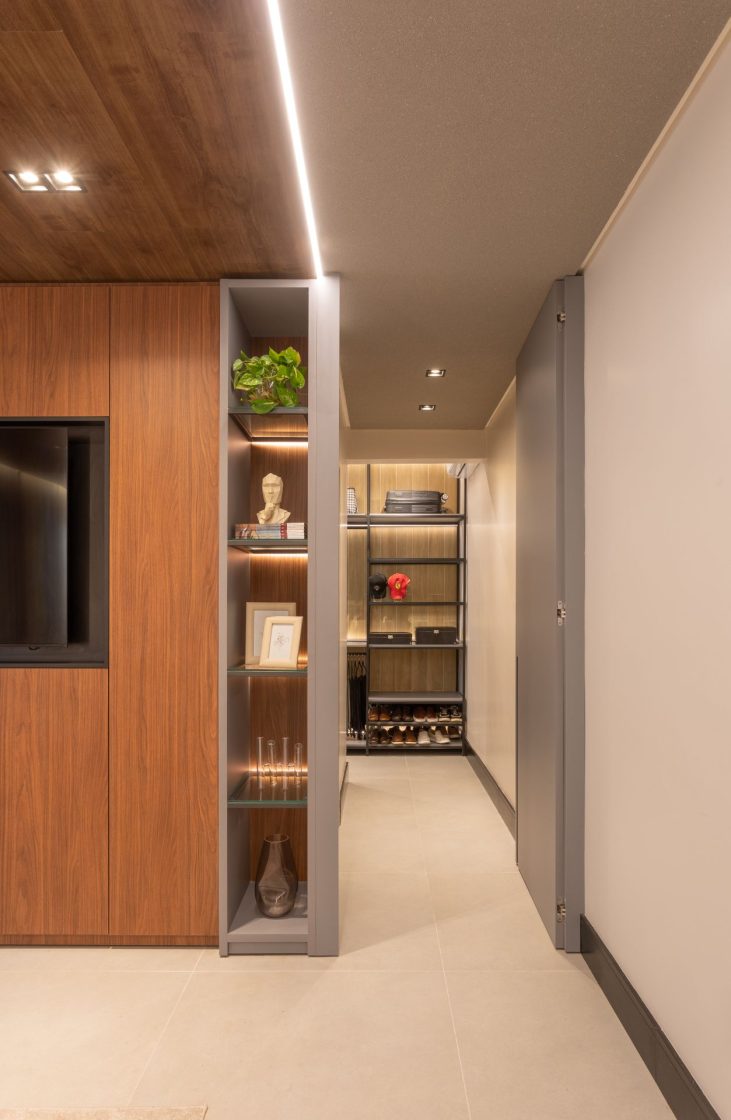 Corredor com closet ao fundo e nichos com objetos decorativos e porta-retratos ao lado da porta