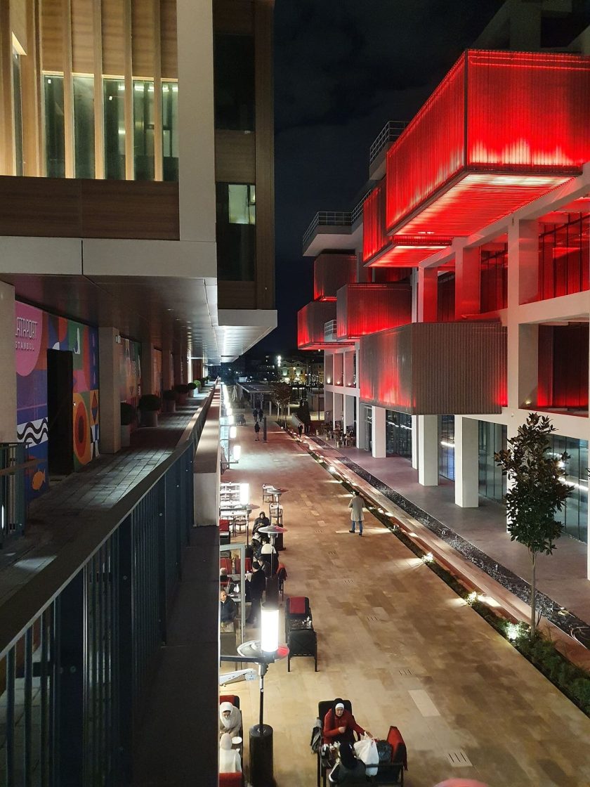 Complexo urbano moderno do Galataport Istanbul à noite, com edifícios iluminados, restaurantes e espaços de convivência