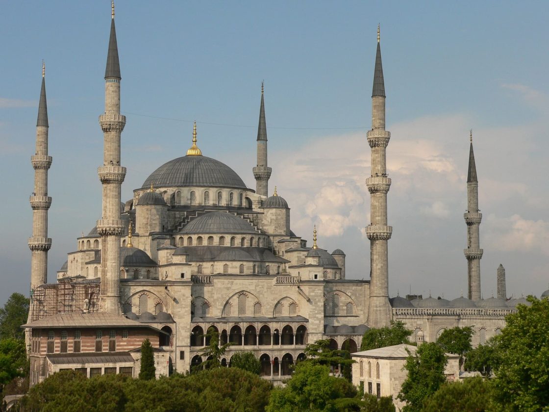 Fachada da Mesquita Azul com múltiplas cúpulas e minaretes sob céu parcialmente nublado em Istambul