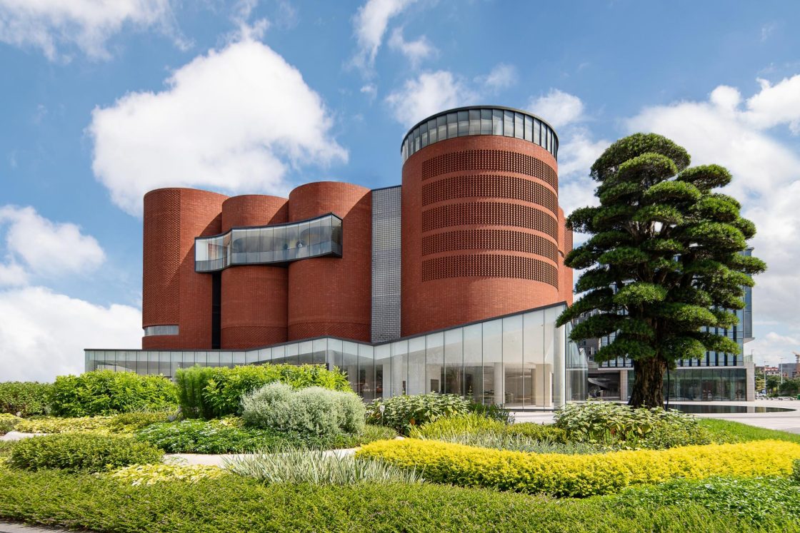 Fachada de museu na China com três volumes cilíndricos revestidos com tijolinho vermelho