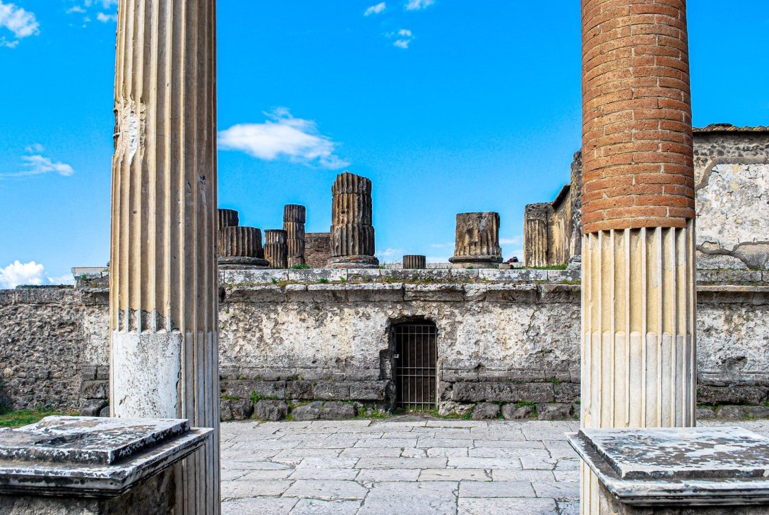 Vista das ruínas de Pompeia, cidade romana preservada pela erupção do Monte Vesúvio em 79 d.C., com colunas, ruas e estruturas que revelam o cotidiano de seus antigos habitantes